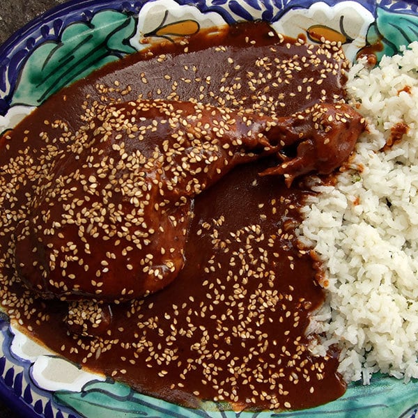 a deep red mole sauce smothered over meat and rice