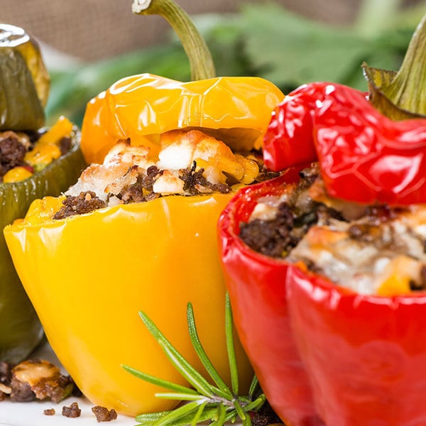 one red and one yellow stuffed pepper filled with ground meat and cheese