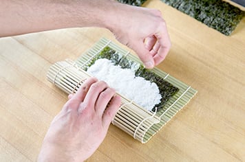 using a bamboo mat to roll futomaki