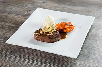 steak, carrots, and whipped potatoes arranged on a white, square plate