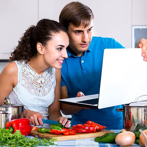 A man showing a female chef a laptop of cooking video