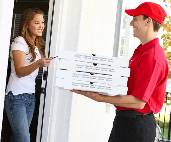 Delivery man handing pizzas to woman who is handing him money