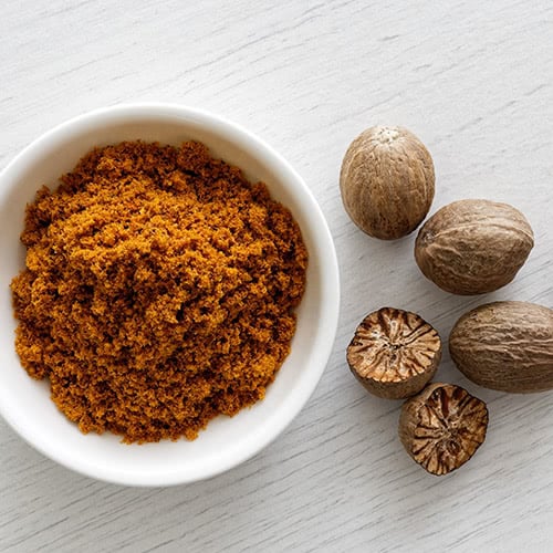 Ground spices in a bowl next to whole spices