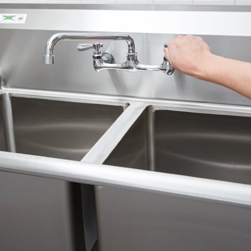 Person filling a 3 compartment sink with water