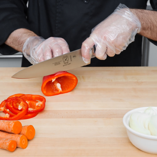 Chef wearing disposable gloves cutting vegetables