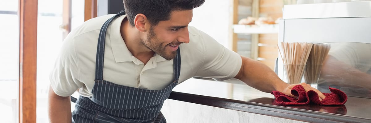 Waiter cleaning countertop with red rag