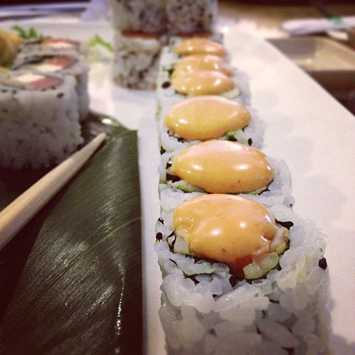 sushi in a line with sauce on top and chopstick next to it