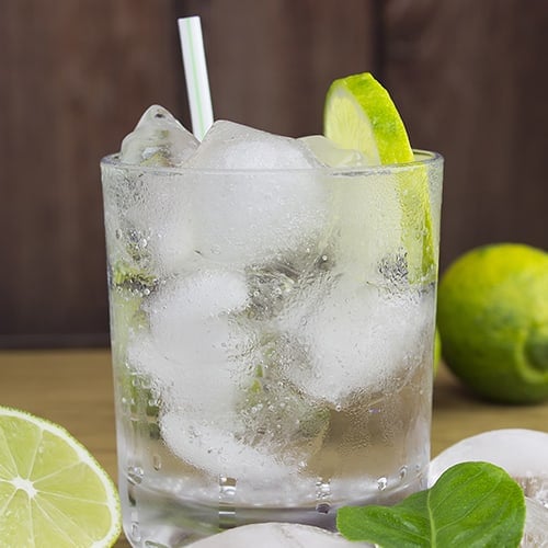 vodka tonic with ice cubes, straw, and lime slice in glass