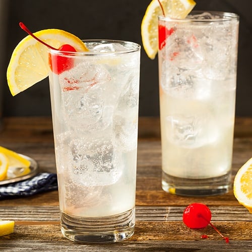 two Tom Collins cocktails with cherries and lemon slices as garnishes