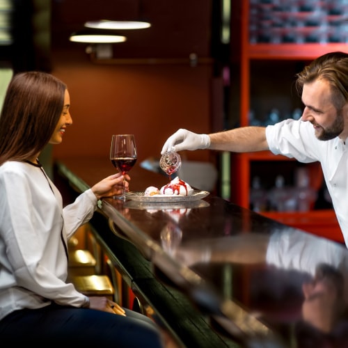 chef pouring syrup onto dessert for a guest dining solo