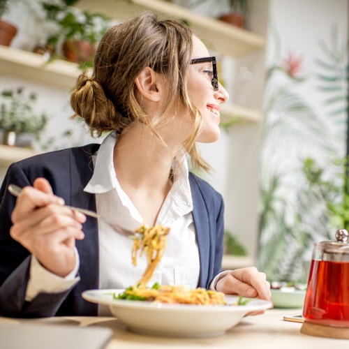 a woman solo dining holding fork over a plate of spaghetti