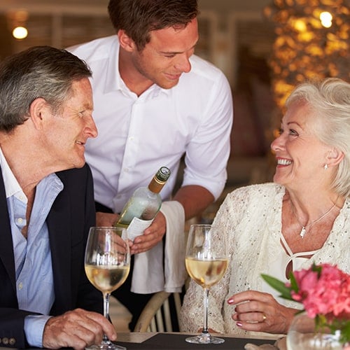 Server smiling after pouring white wine to a happy couple