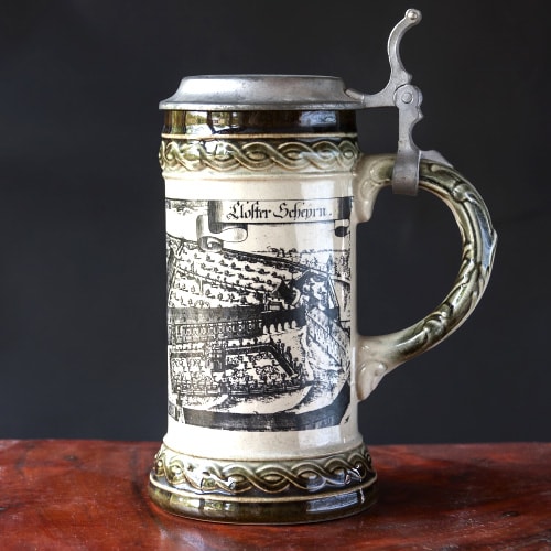 Decorative pewter beer stein with intricate artwork and a thumb lever-operated lid