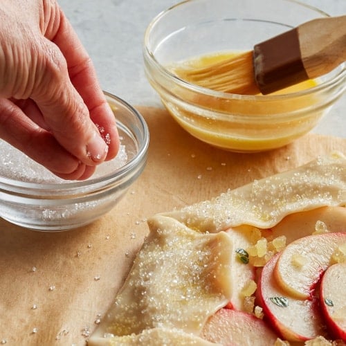 sanding sugar being sprinkled to a peach galette