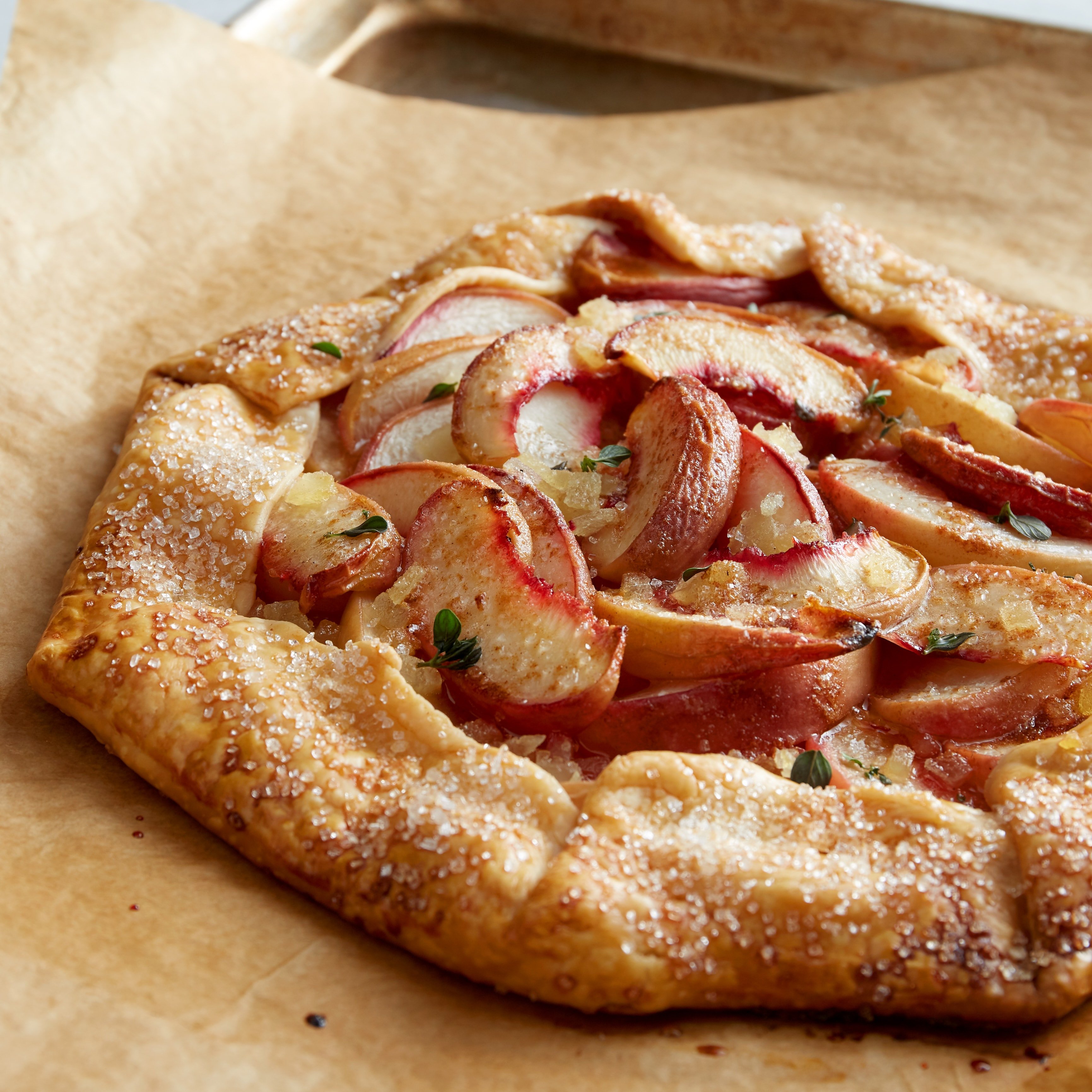A browned galette tarte with cooked peaches, candied ginger, and thyme