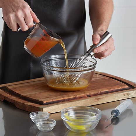 A chef mixing apple cider with other spices in a bowl