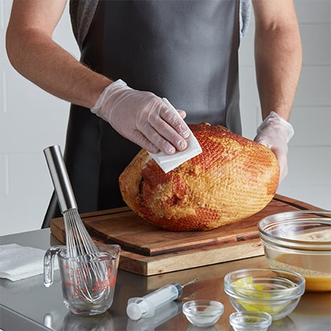 A chef drying a ham with a lint-free towel