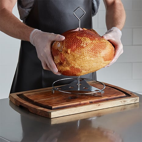 A chef sliding a ham onto a poultry wrack.
