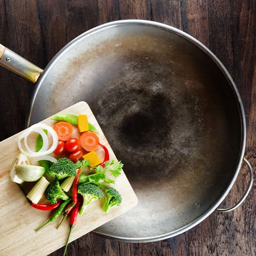 Cut up vegetables on a cutting board over a wok