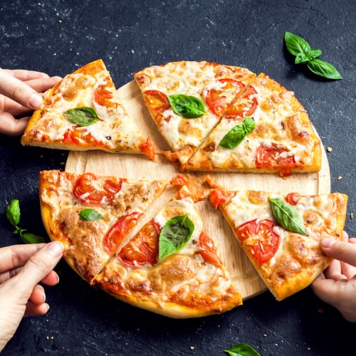 overhead view of pizza with three hands each pulling out a slice