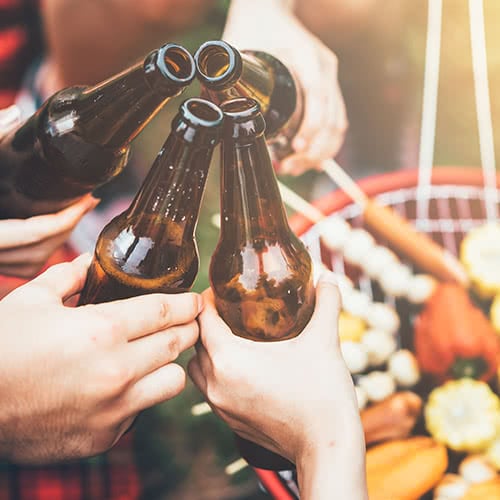 Four hands clinking beer bottles together for a cheers