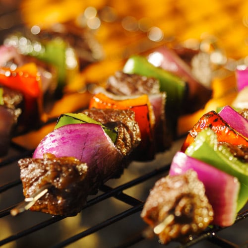 Kabobs of beef, onion, and peppers on an open flame grill