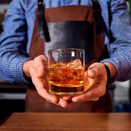 a bartender presenting a completed mixed drink