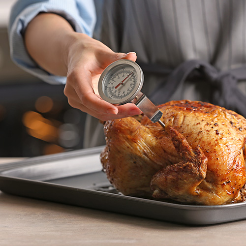 Chef holding meat thermometer in cooked turkey