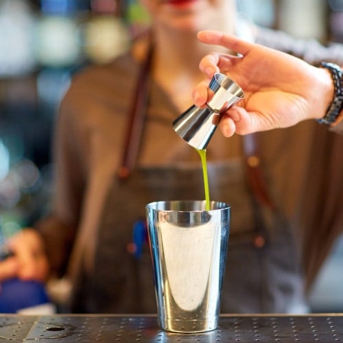 Woman using a jigger to make a cocktail