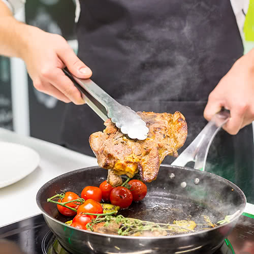 Cooking chicken and vegetables on the stove in a pan