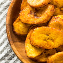 a wooden bowl filled with fried slices of tajadas plantains