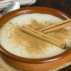 a bowl of rice pudding topped with cinnamon sticks