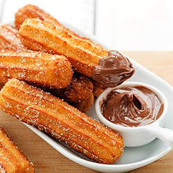 a serving plate filled with crispy golden churros and chocolate dipping sauce