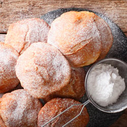 a stack of round fried dough fritters dusted with sugar