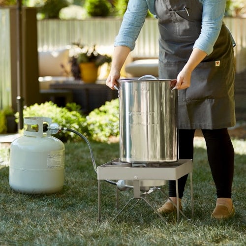 stainless steel pot on turkey fryer with small flame outdoors