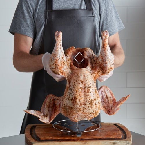man lifting turkey covered in seasoning