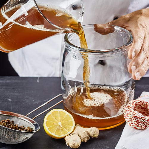 amber liquid being poured into a wide-mouth jar