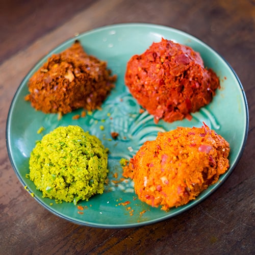 Four different color curry pastes on a plate