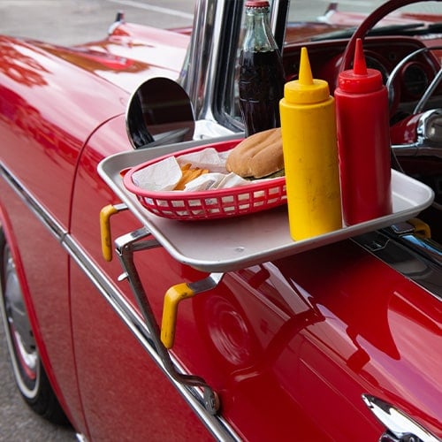 Food tray in window of car with burger and fries