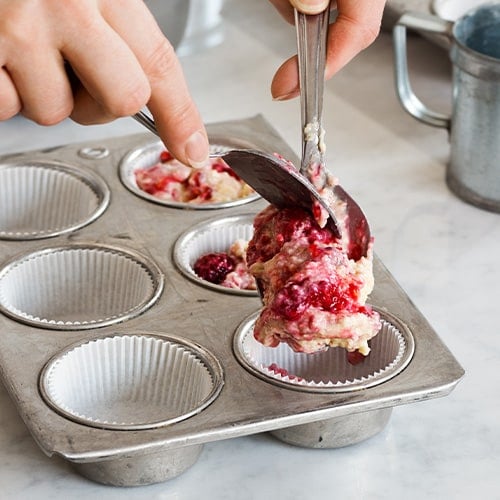 Dropping cupcake batter from a spoon into a cupcake tin