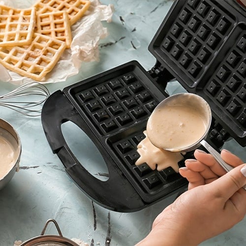 Pouring waffle batter into a waffle maker