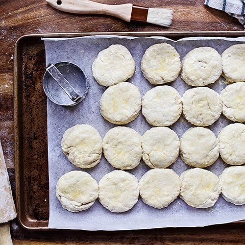 Buttermilk biscuit dough lined on a baking sheet