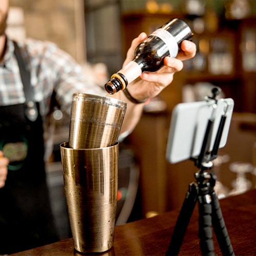 Bartender filmándose a sí mismo con un smarphone en un trípode