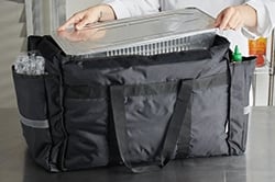 Chef putting food pan into large black food storage bag