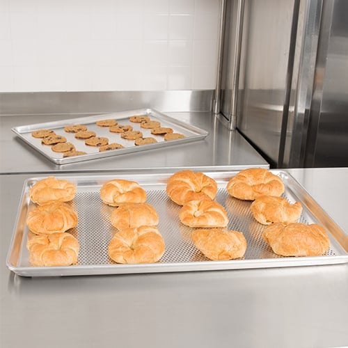 Two baking sheets on a stainless steel countertop