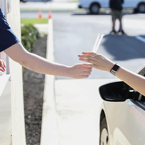 Drive-thru worker hands a customer a two straws from a drive-thru window