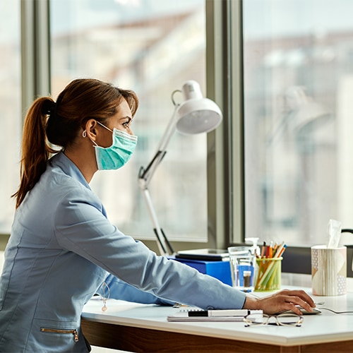 Woman wearing face mask at desk.