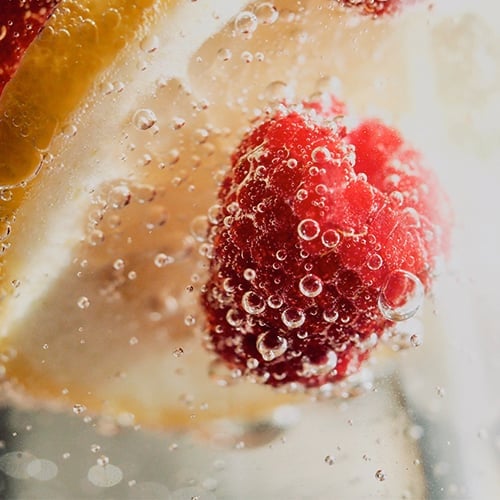 raspberry and orange peel floating in seltzer