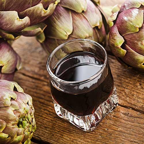 amaro on wood table with artichoke background