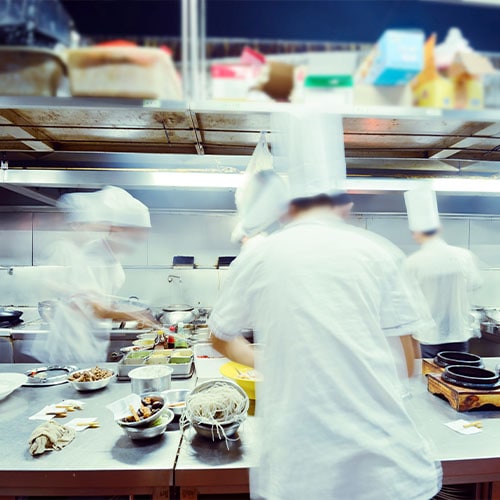 chef prepares food in a busy commercial kitchen